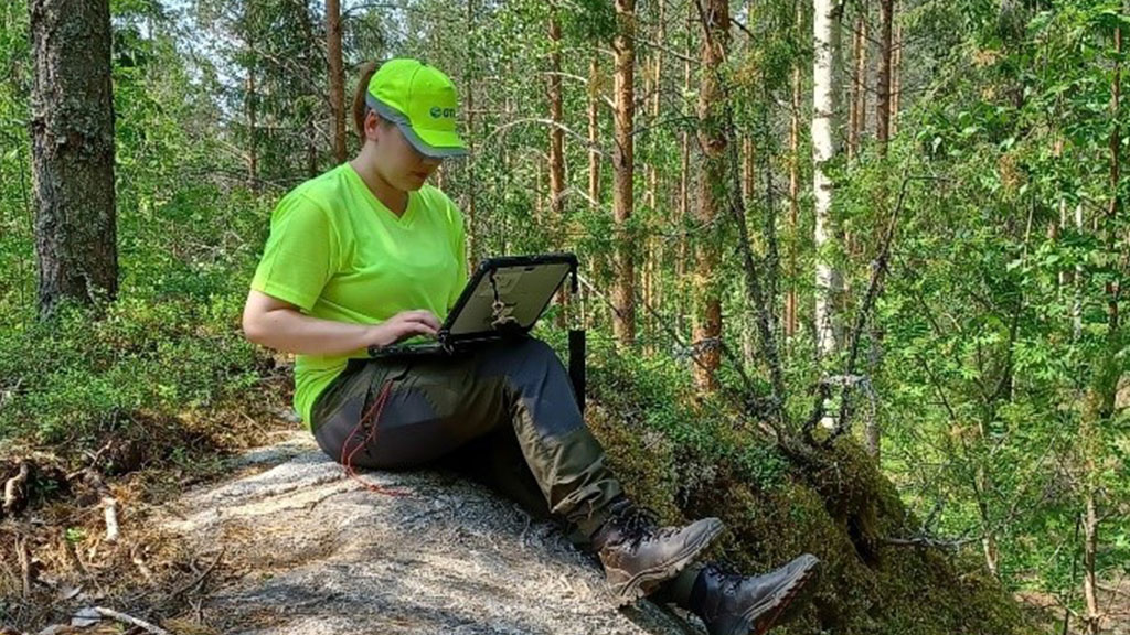 Kesäharjoitelija Venla Vehanen tallentaa havaintoja kalliolla istuen.