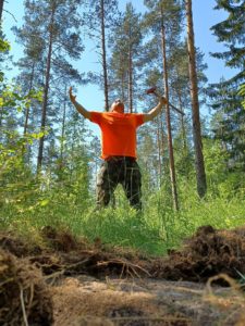 Man in an orange shirt spreads arms in forest