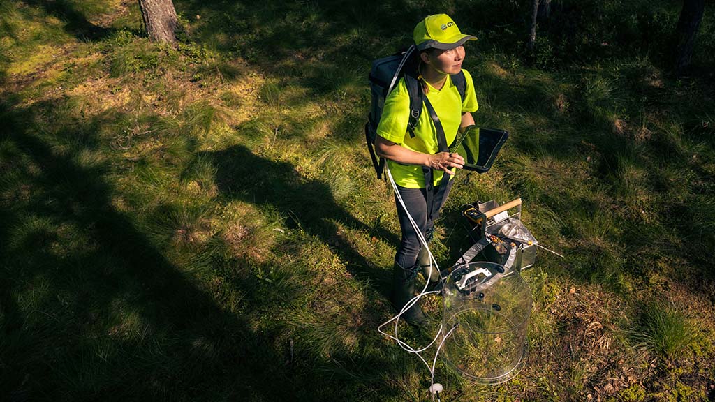 Tutkija ja kasvihuonekaasujen mittauslaitteisto metsässä.