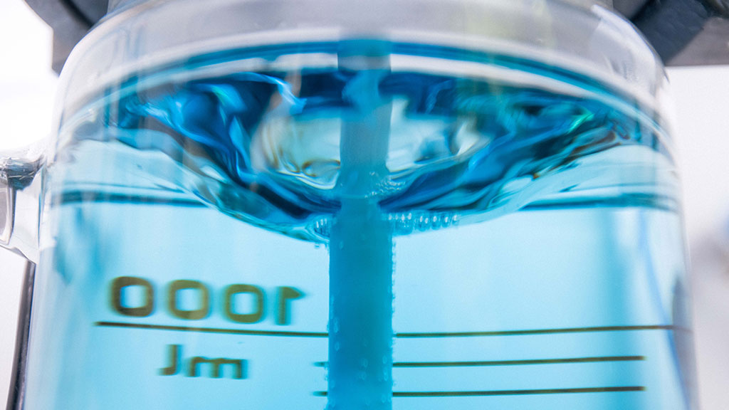 Lähikuva laboratoriopullosta, jossa on sinistä läpikuultavaa nestettä.
