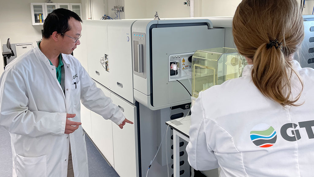 A large laboratory equipment. Two persons in laboratory coats are working with the equipment.