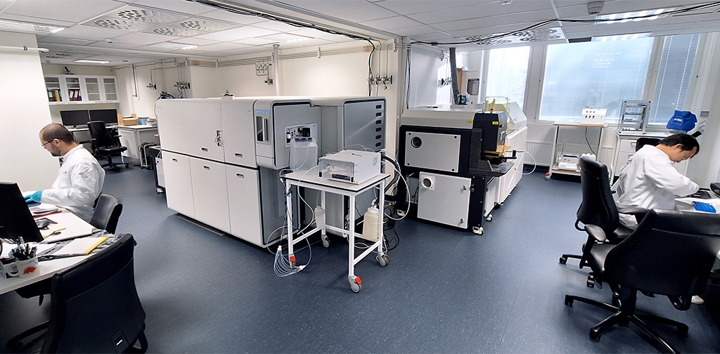 A room with laboratory equipment and two people examining samples at the table.